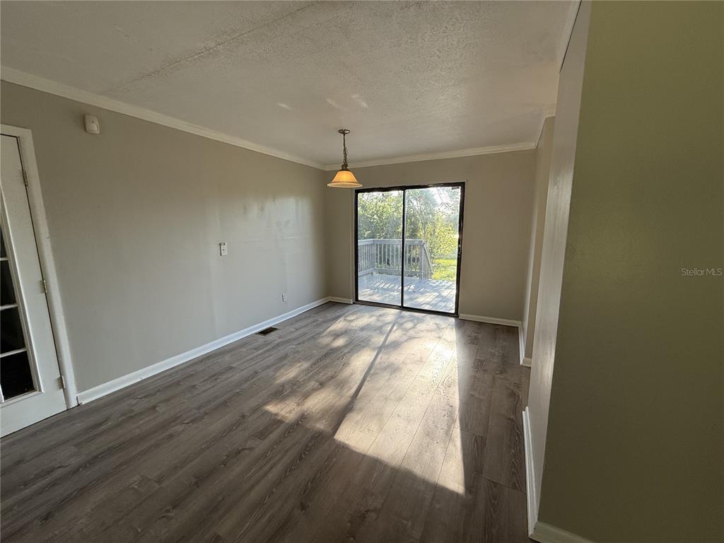 An empty dining room features gray wood-look flooring, a pendant light, and sliding glass doors — 307 S ORANGE AVENUE, DELAND, FL