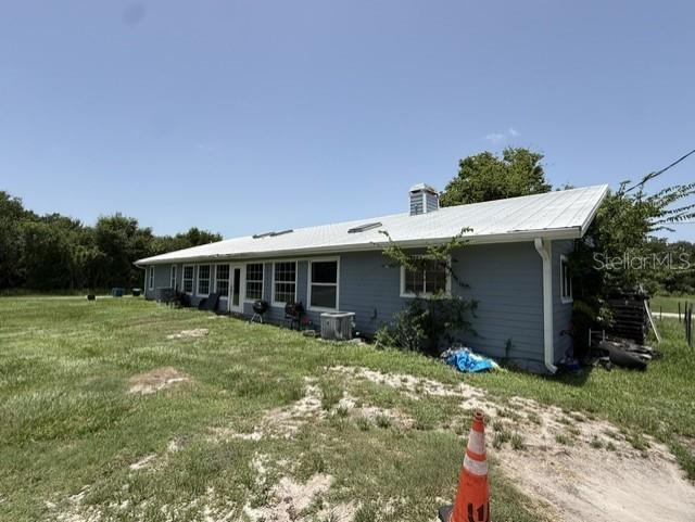 A single-story gray house with a metal roof sits on a grassy lot — 1292 VALLEYBROOK ROAD SE, PALM BAY, FL