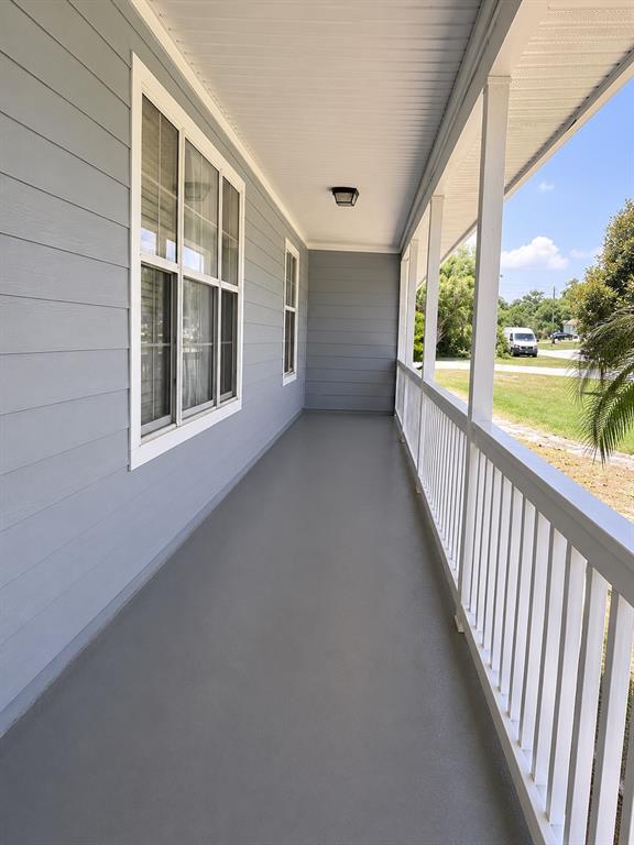 A covered porch with gray siding, white railings, and a smooth gray floor — 1292 VALLEYBROOK ROAD SE, PALM BAY, FL