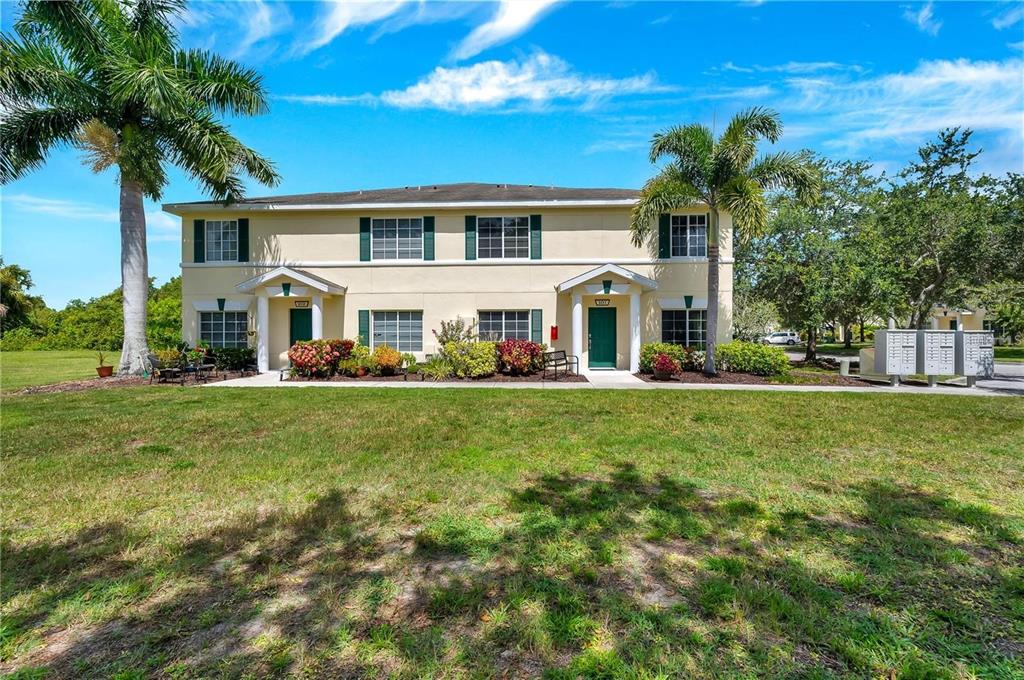 A two-story tan townhouse with green shutters, a palm tree, and a grassy front yard — 280 CAPE HARBOUR LOOP UNIT 101, BRADENTON, FL