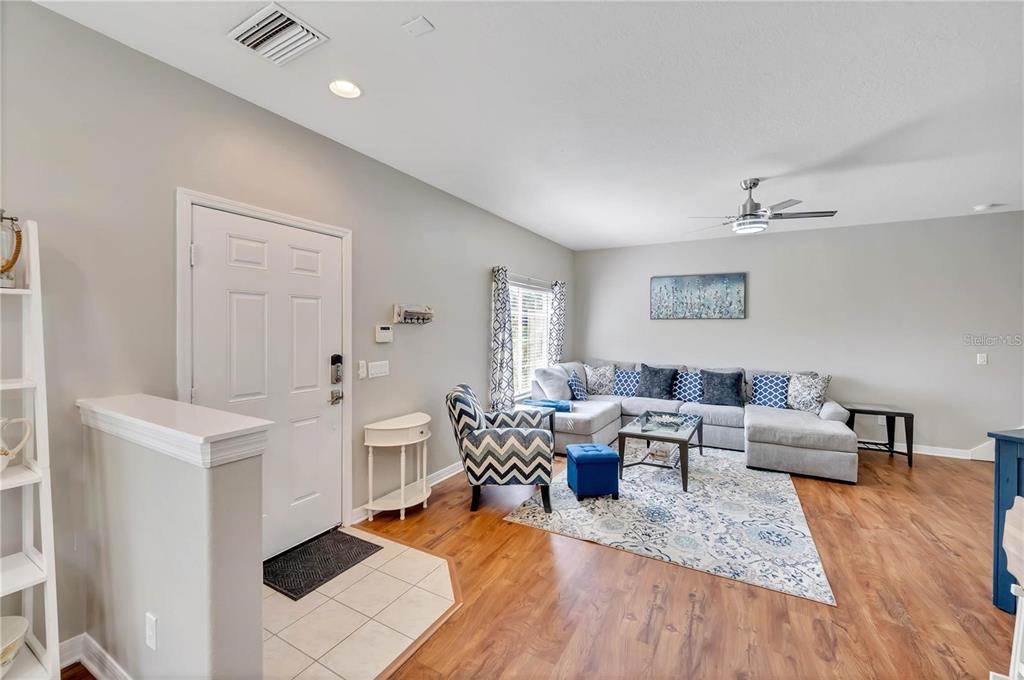 A living room features light gray walls, wood-look flooring, a sectional sofa, and an entryway — 280 CAPE HARBOUR LOOP UNIT 101, BRADENTON, FL
