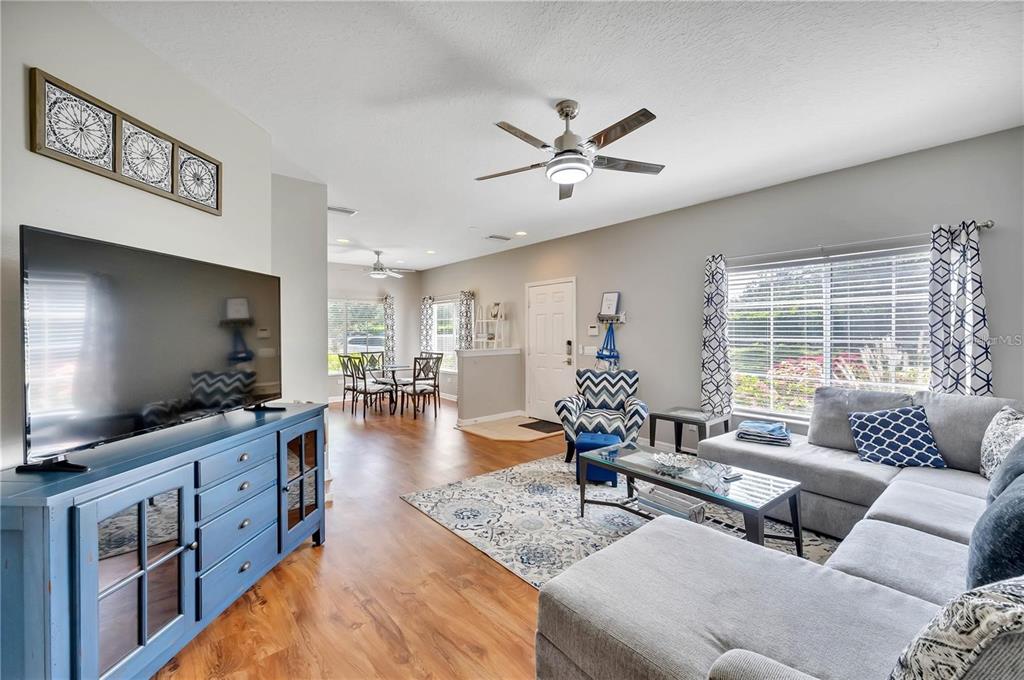A living room features a blue media console, a grey sectional sofa, and a dining area — 280 CAPE HARBOUR LOOP UNIT 101, BRADENTON, FL