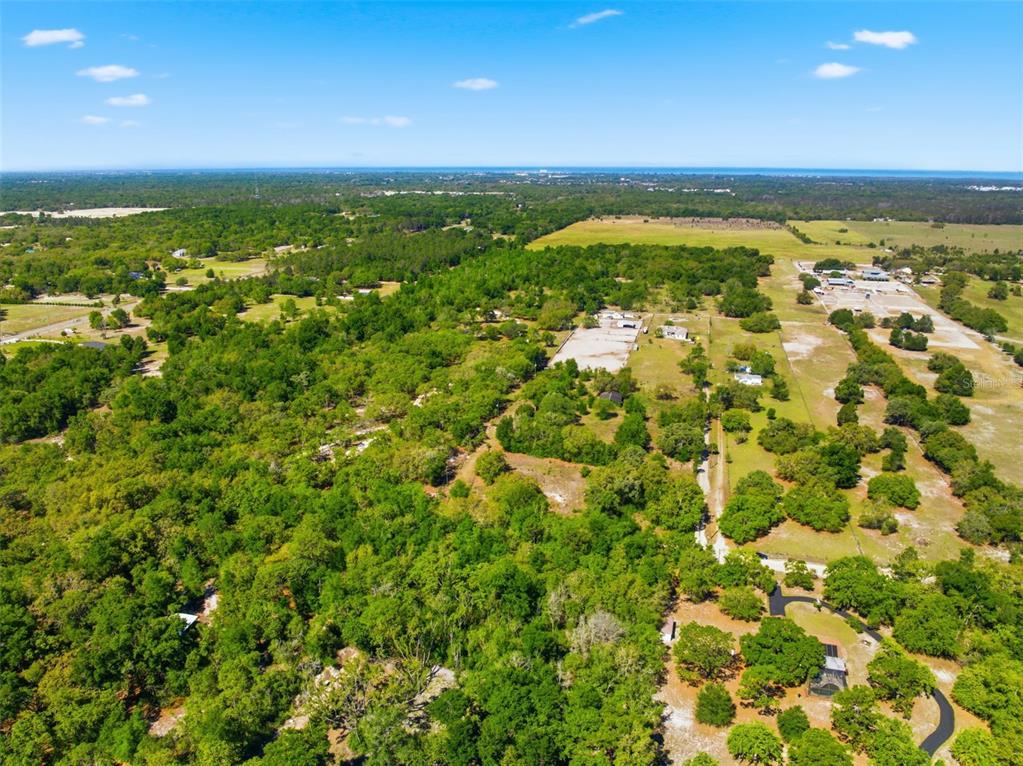 An aerial view shows a large, wooded rural property with scattered buildings and open fields — 0 COYOTE ROAD, HUDSON, FL