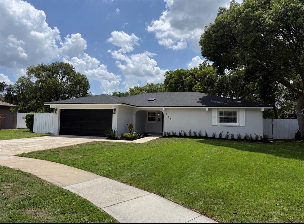 A single-story house with a gray exterior, black garage door, and a dark shingled roof — 726 FOREST GLEN COURT, MAITLAND, FL