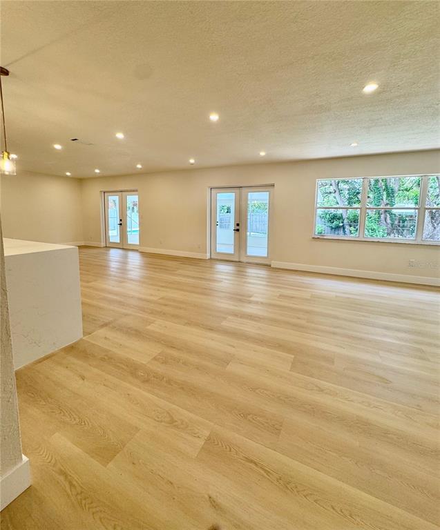 A spacious, open-concept room features light wood flooring, recessed lighting, and two sets of doors — 726 FOREST GLEN COURT, MAITLAND, FL