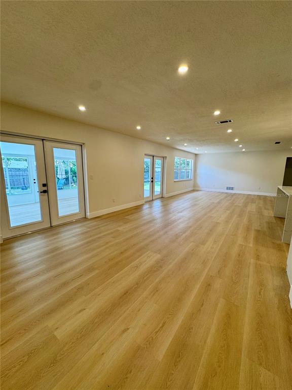 A spacious room features light wood-look flooring, recessed lighting, and two sets of glass doors — 726 FOREST GLEN COURT, MAITLAND, FL
