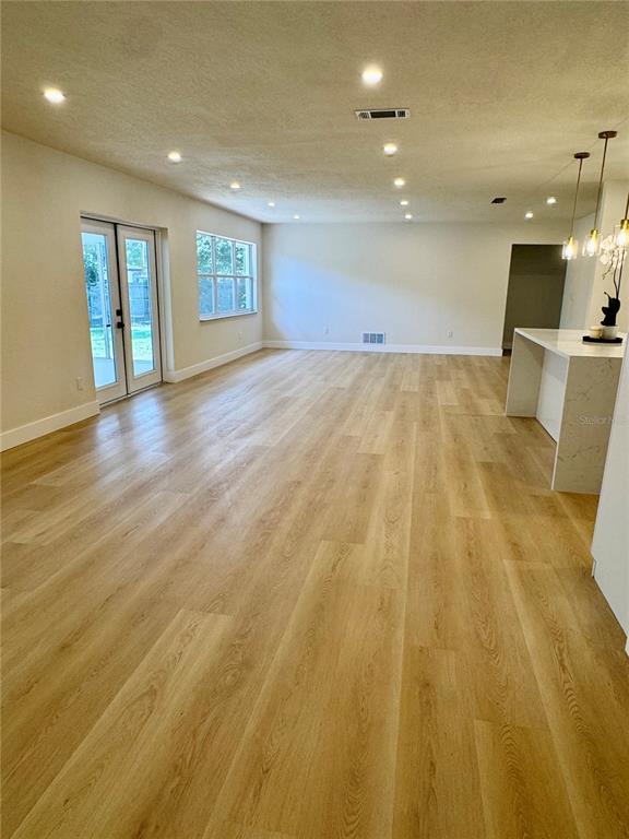 A spacious, open-concept living area features light wood-look flooring, recessed lighting, and a kitchen island — 726 FOREST GLEN COURT, MAITLAND, FL