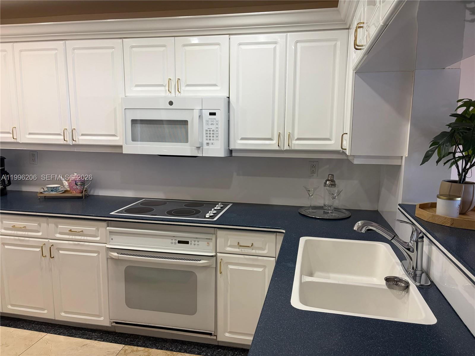A kitchen features white cabinetry, a dark blue countertop, and a white double-basin sink — 1717 N Bayshore Dr # 2254, Miami FL 33132, MIAMI, FL