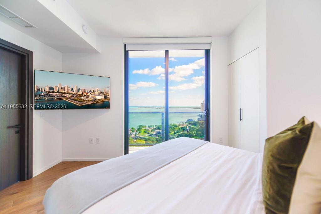 A bedroom features a bed, a wall-mounted television, and a balcony overlooking the ocean — 398 NE 5th St # 2314, Miami FL 33132, MIAMI, FL