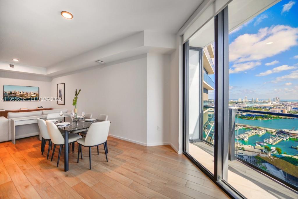 A dining area with a glass table and chairs overlooks a harbor and city skyline — 398 NE 5th St # 2314, Miami FL 33132, MIAMI, FL
