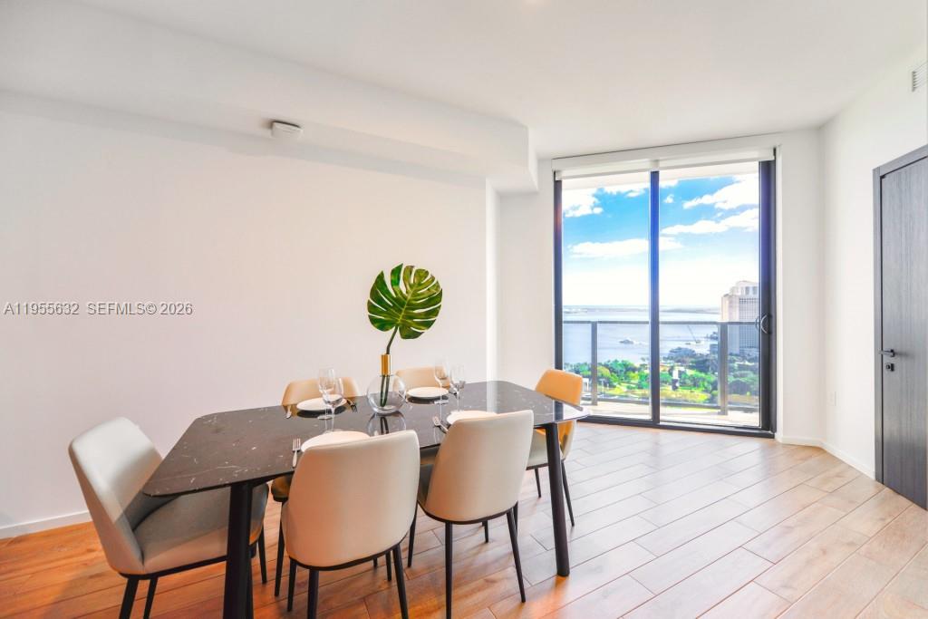 A dining room features a black marble table, light-colored chairs, and floor-to-ceiling windows with water views — 398 NE 5th St # 2314, Miami FL 33132, MIAMI, FL