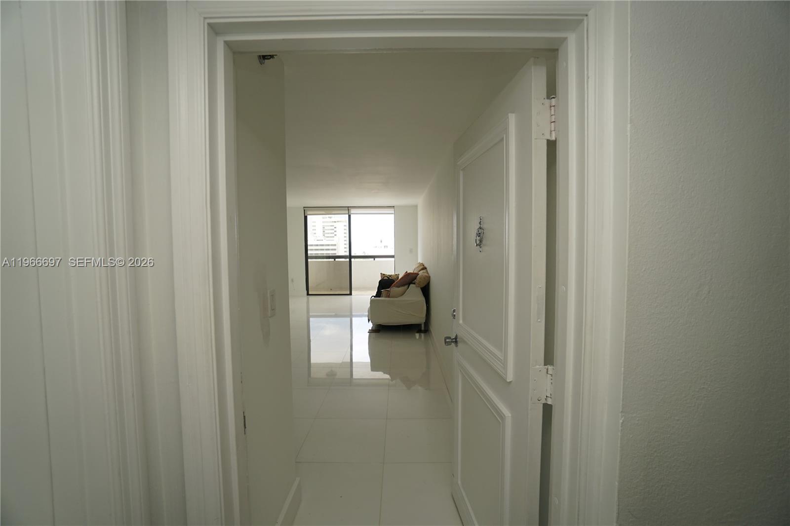 A view through an open doorway reveals a bright living area with white tile floors — 1775 Washington Ave # 11C, Miami Beach FL 33139, MIAMI BEACH, FL