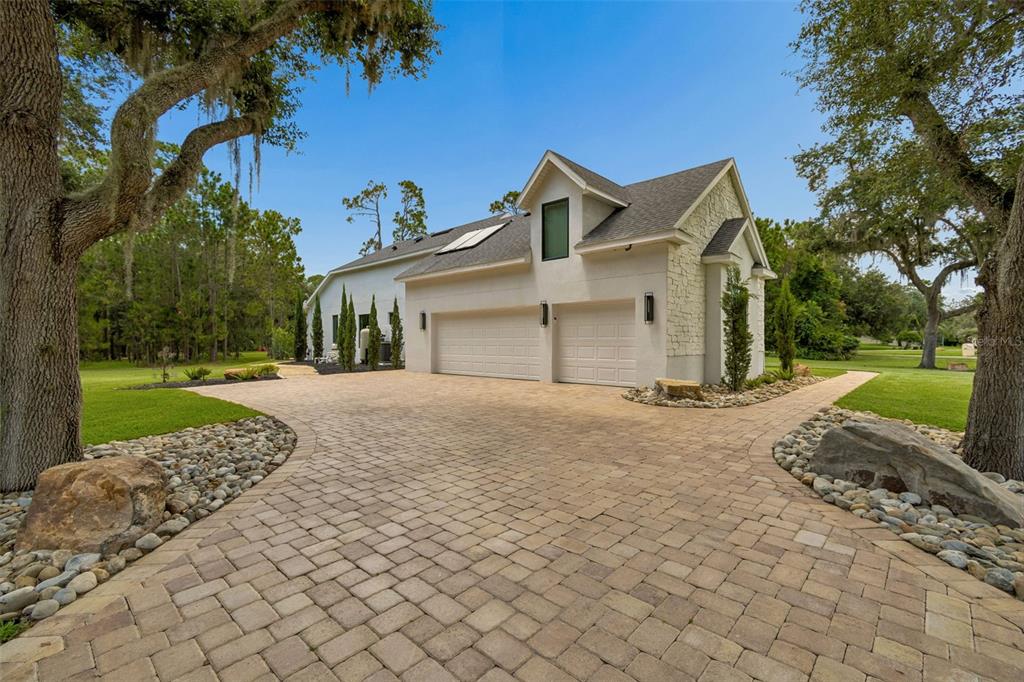 A paved driveway leads to a two-car garage of a white house with stone accents — 13961 SMOKERISE COURT, ORLANDO, FL