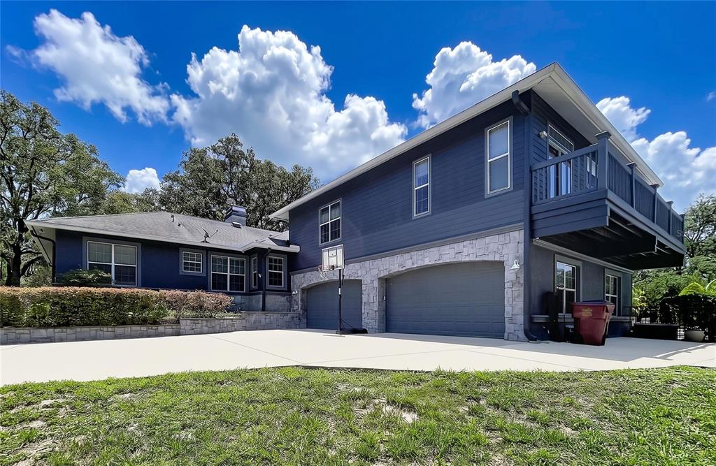 A two-story blue house with a stone-accented garage and a second-story balcony — 2918 MAGNOLIA TRACE, TARPON SPRINGS, FL