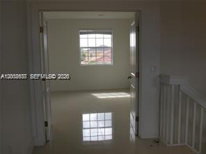 A view through double doors into a room with light tile flooring and a window — 15650 SW 11th Ter # 0, Miami FL 33194, MIAMI, FL