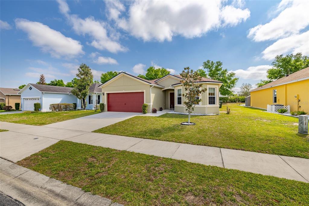 A single-story house with a red garage door and a light green exterior — 1325 CYPRESS RIDGE LOOP, LAKE ALFRED, FL