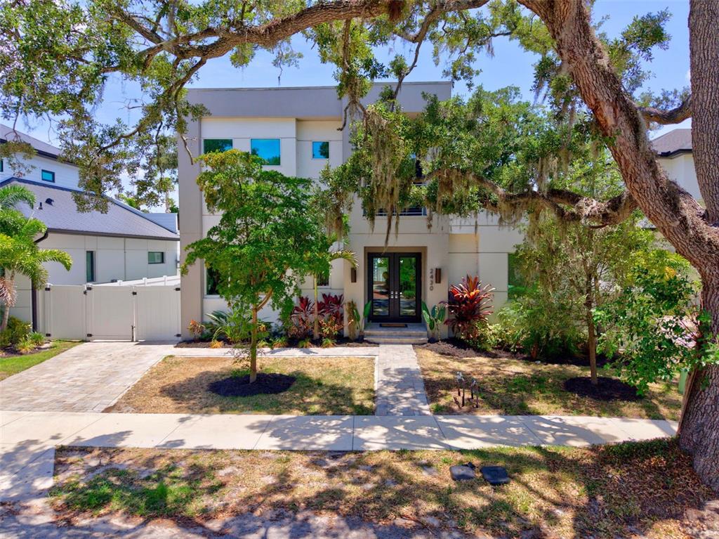 A modern, two-story house with a paved walkway and landscaping under large oak trees — 2430 FLOYD STREET, SARASOTA, FL