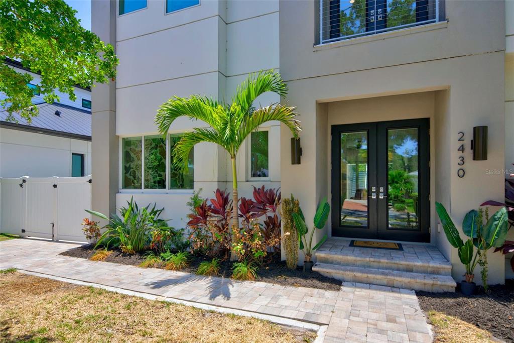 The exterior of a modern home features a palm tree, landscaping, and a double-door entrance — 2430 FLOYD STREET, SARASOTA, FL