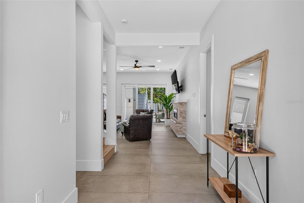 A hallway with tile flooring leads to a living area with a fireplace and patio doors — 2430 FLOYD STREET, SARASOTA, FL