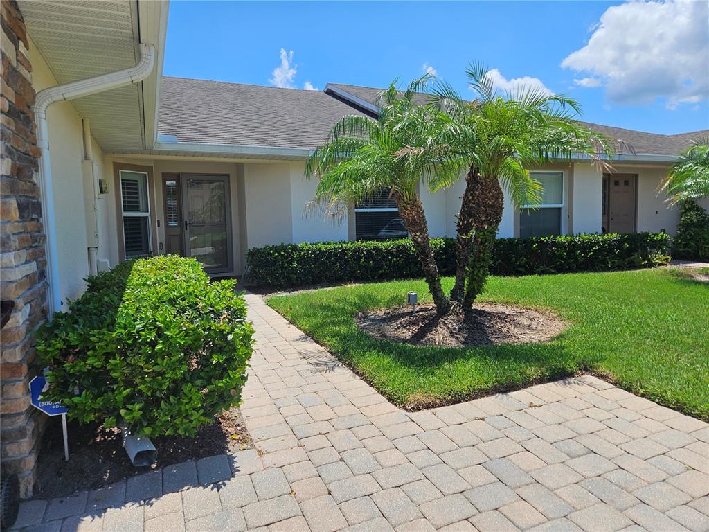 A paved walkway leads to the front entrance of a single-story house with landscaping — 2696 SHELBY RUTH PLACE, ST CLOUD, FL