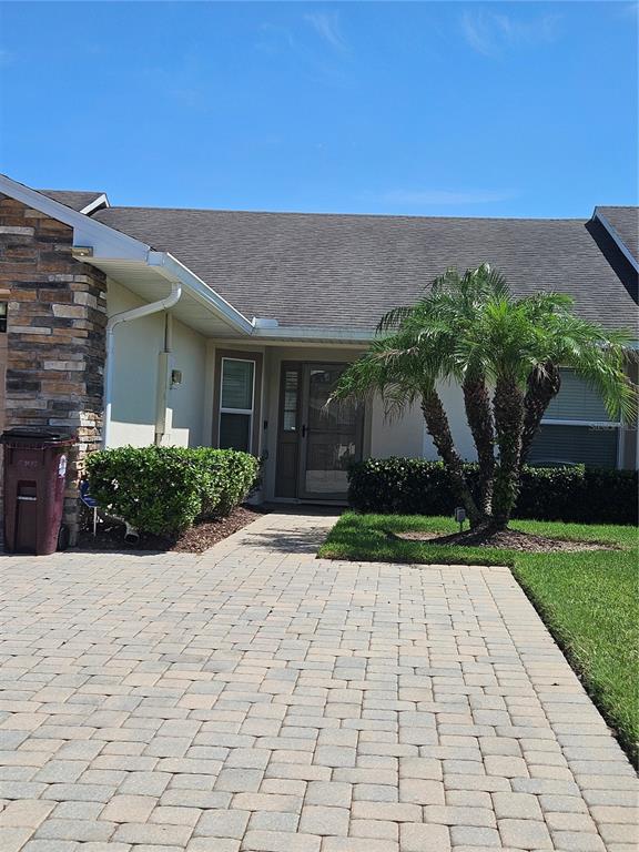 A stone-accented house exterior features a paved driveway, a palm tree, and a front entrance — 2696 SHELBY RUTH PLACE, ST CLOUD, FL