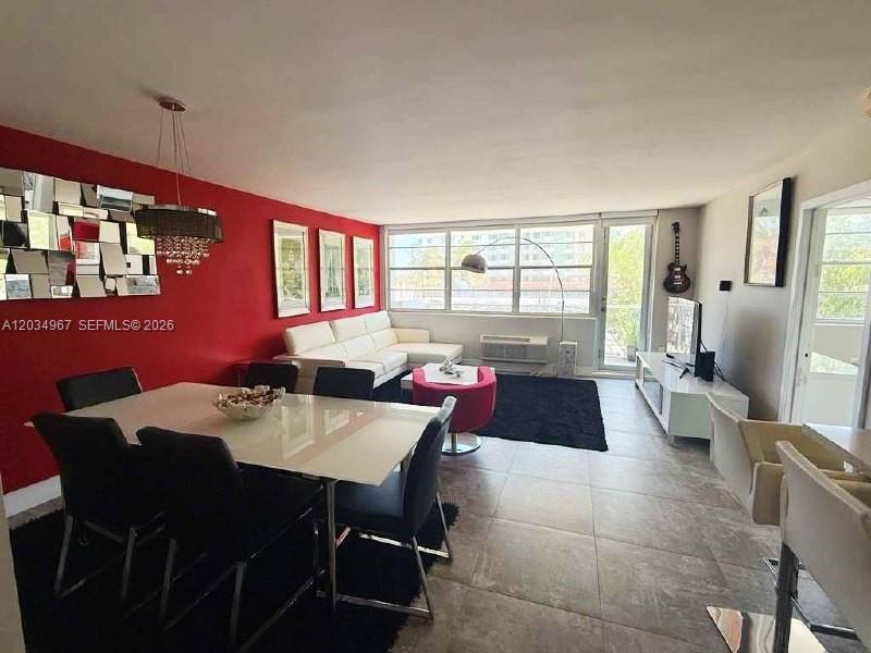 A dining area and living room feature a red accent wall, tile floors, and windows — MIAMI BEACH, FL