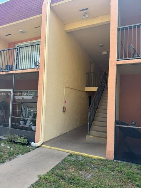 An exterior view of a two-story apartment building featuring a central staircase and screened balconies — 2970 NW 55th Ave # 2C, Lauderhill FL 33313, LAUDERHILL, FL