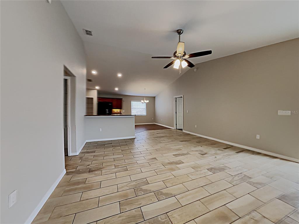An open-concept living area features light-colored tile flooring, a ceiling fan, and a kitchen island — 3030 GRAND PRESERVE BOULEVARD, MULBERRY, FL