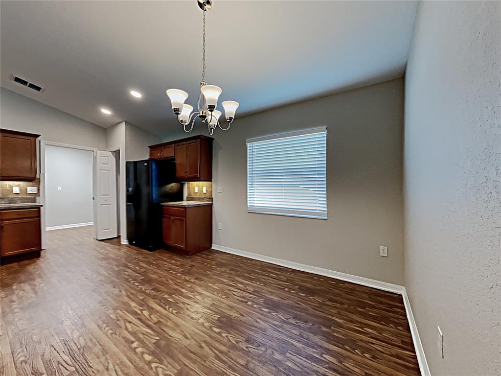 A dining area with wood-look flooring, a chandelier, and dark wood kitchen cabinets — 3030 GRAND PRESERVE BOULEVARD, MULBERRY, FL