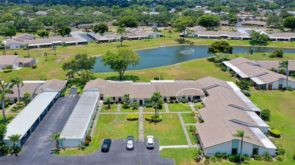 An aerial view shows a residential complex with a central pond and parking areas — 6129 HERITAGE LANE W UNIT 6129, BRADENTON, FL