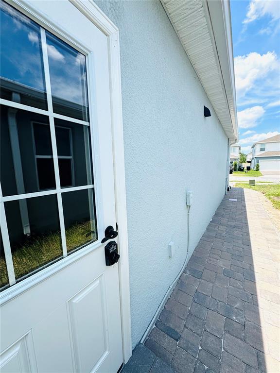 A white door with a keypad lock opens onto a stone paver walkway — 1433 GRAND PALM DRIVE, ORLANDO, FL