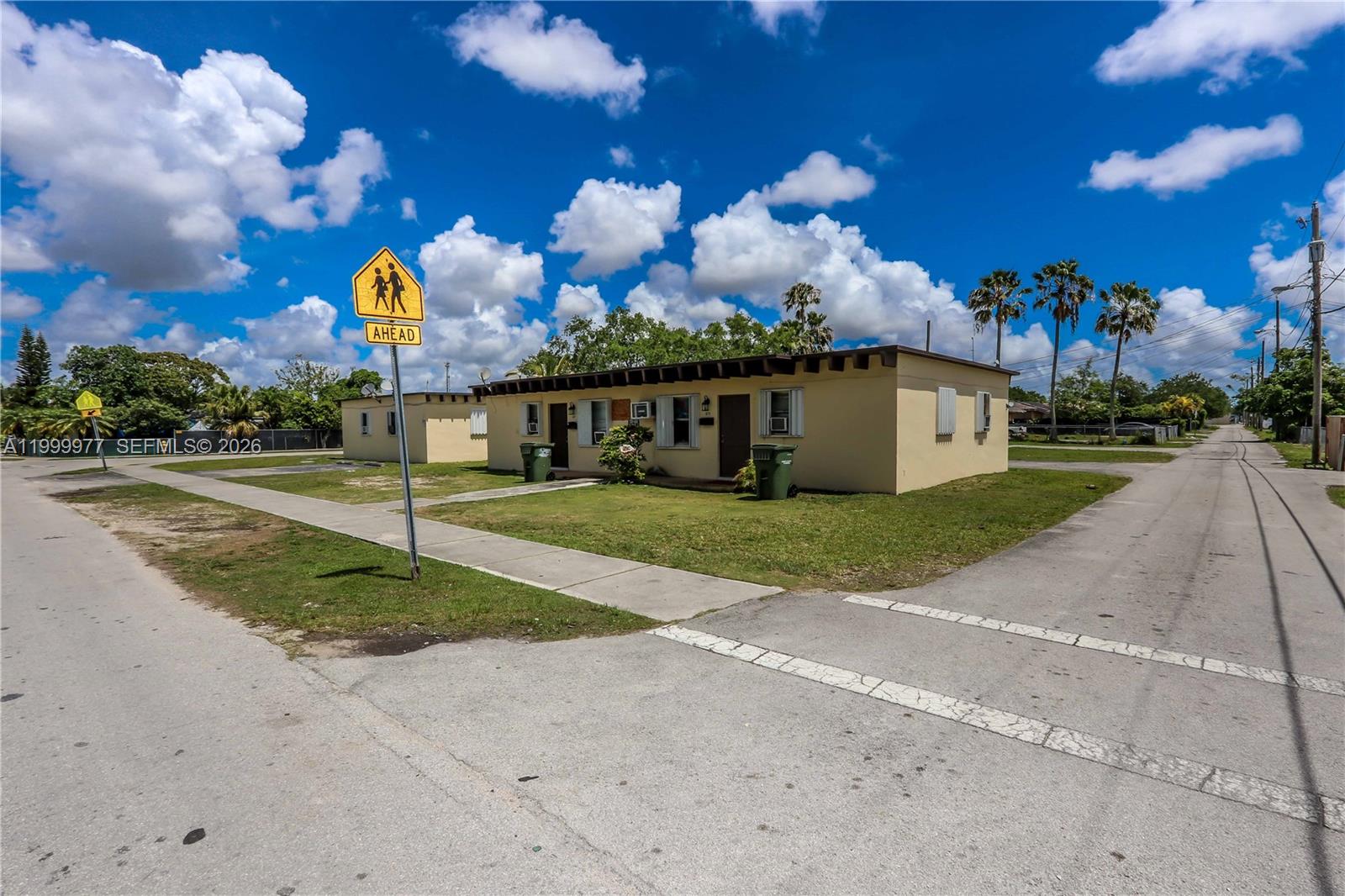 A single-story, light-colored residential building sits on a corner lot near a street sign — 611 SW 8th Ave, Homestead FL 33030, HOMESTEAD, FL