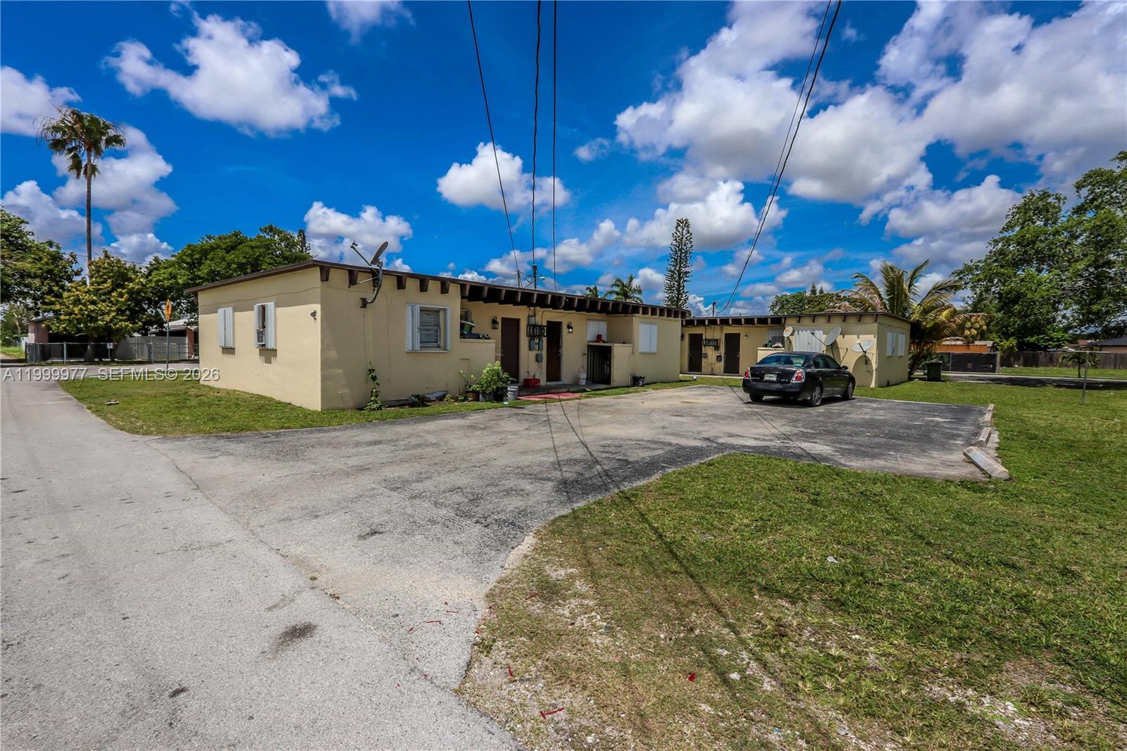 A single-story, light-yellow residential building with a paved driveway and a parked black car — 611 SW 8th Ave, Homestead FL 33030, HOMESTEAD, FL