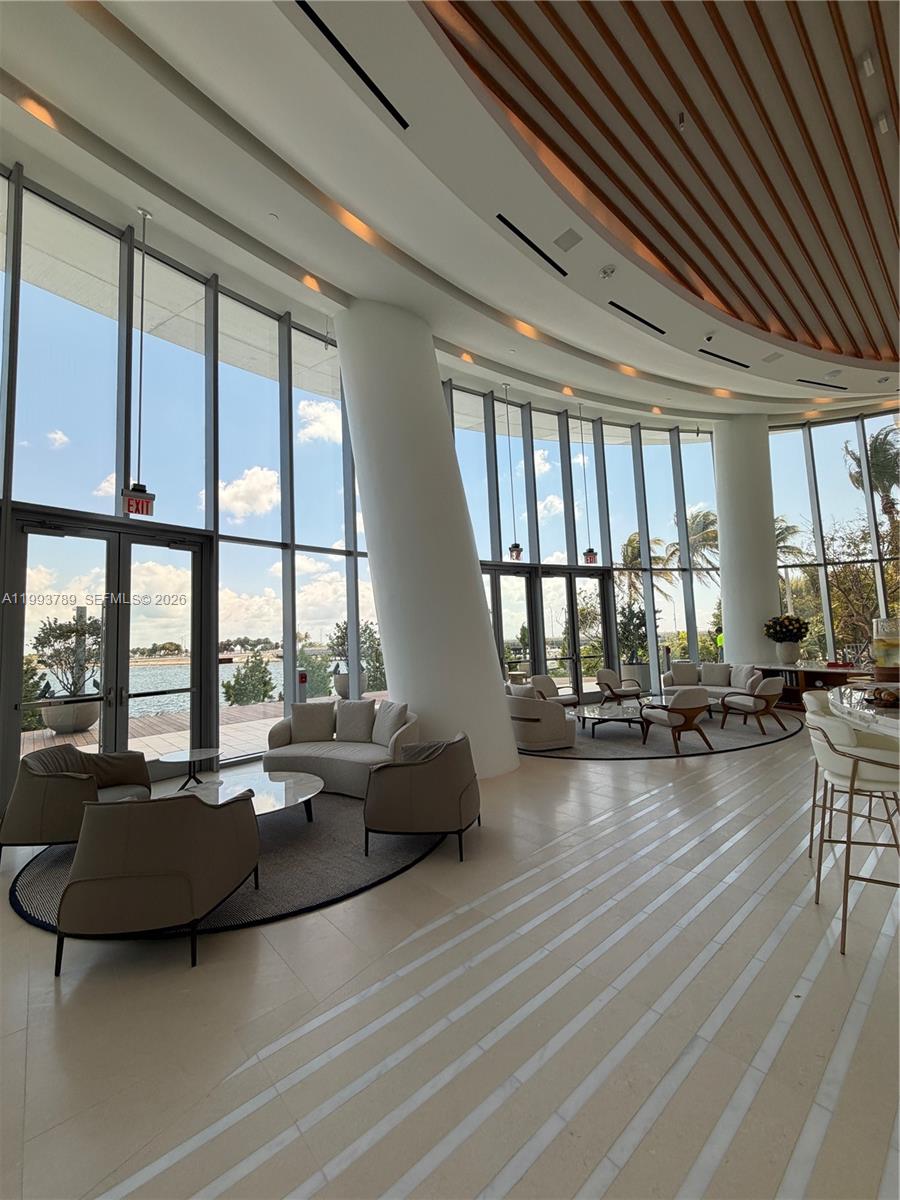 A modern lounge area features floor-to-ceiling windows, curved seating arrangements, and views of water — 175 SE 25th Rd # 2101, Miami FL 33129, MIAMI, FL