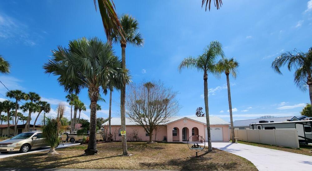A single-story pink house with a metal roof and palm trees in the front yard — 1177 Lisa Lane, Okeechobee FL 34974, OKEECHOBEE, FL
