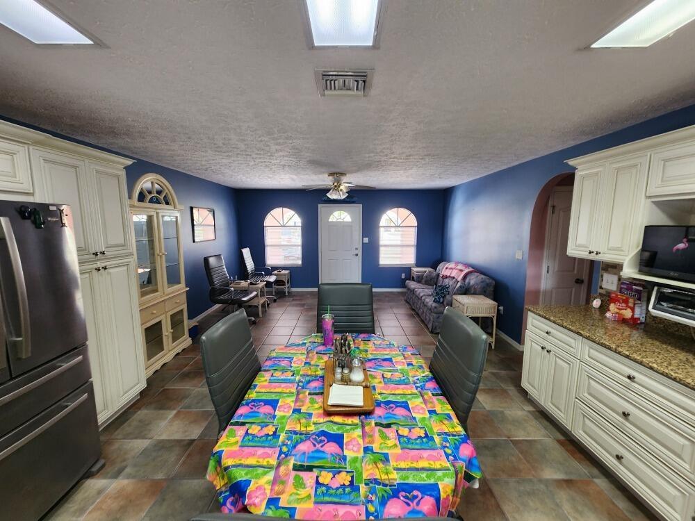 A kitchen and dining area with blue walls, tile floors, and off-white cabinetry — 1177 Lisa Lane, Okeechobee FL 34974, OKEECHOBEE, FL