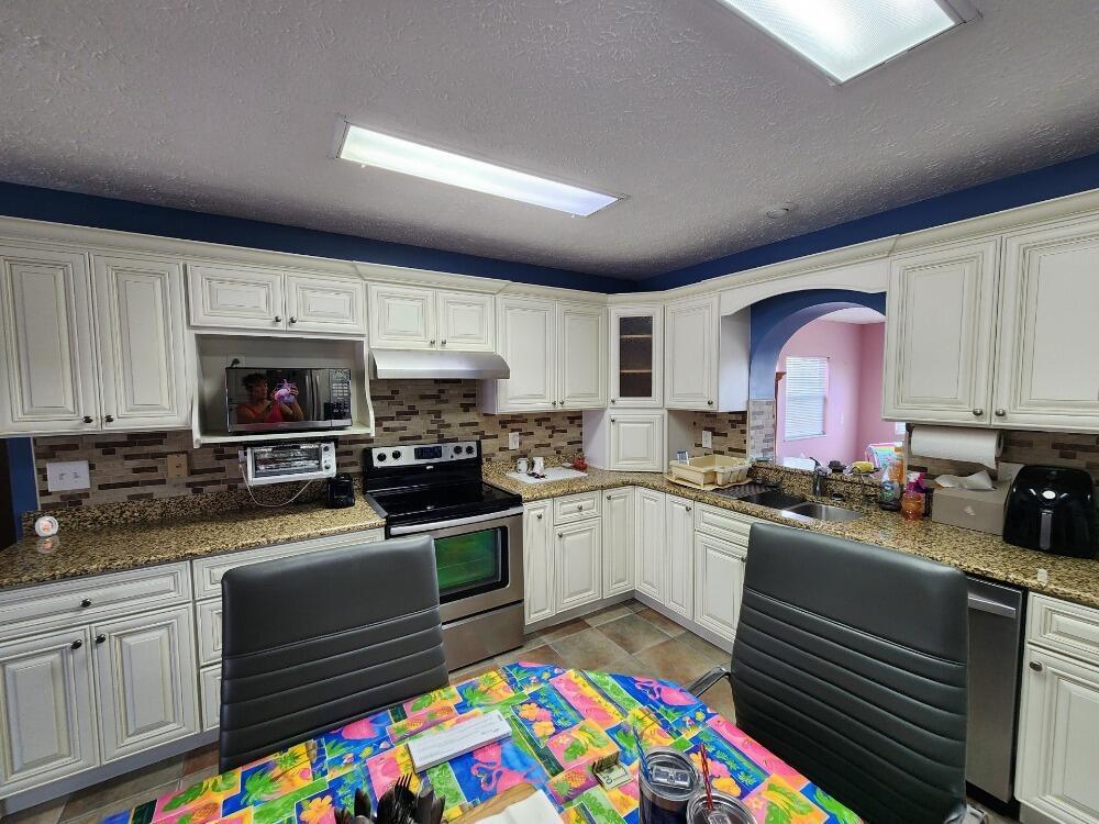 A kitchen with white cabinets, granite countertops, stainless steel appliances, and a tiled backsplash — 1177 Lisa Lane, Okeechobee FL 34974, OKEECHOBEE, FL