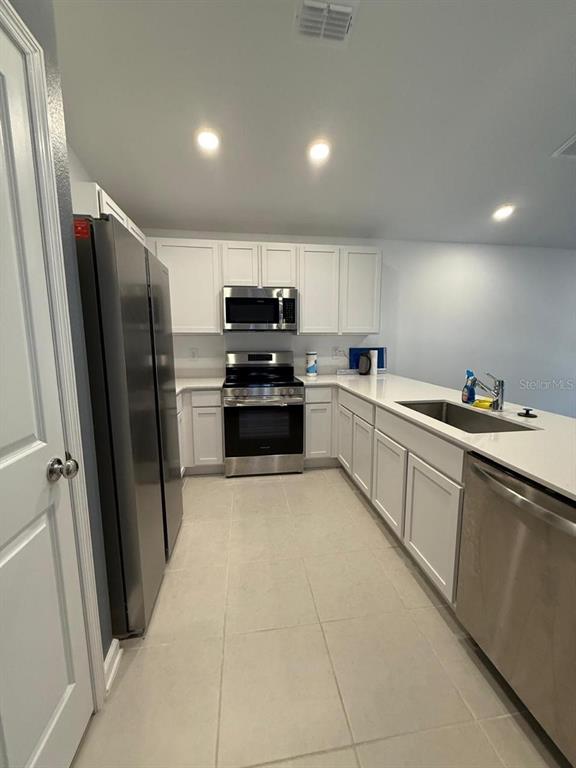 A modern kitchen features white cabinets, stainless steel appliances, and light-colored tile flooring — 1970 SARAH STREET, WINTER HAVEN, FL