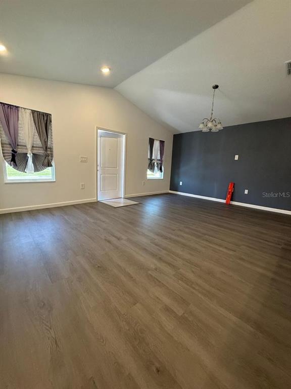 A spacious living room features vaulted ceilings, wood-look flooring, and a dark accent wall — 1970 SARAH STREET, WINTER HAVEN, FL