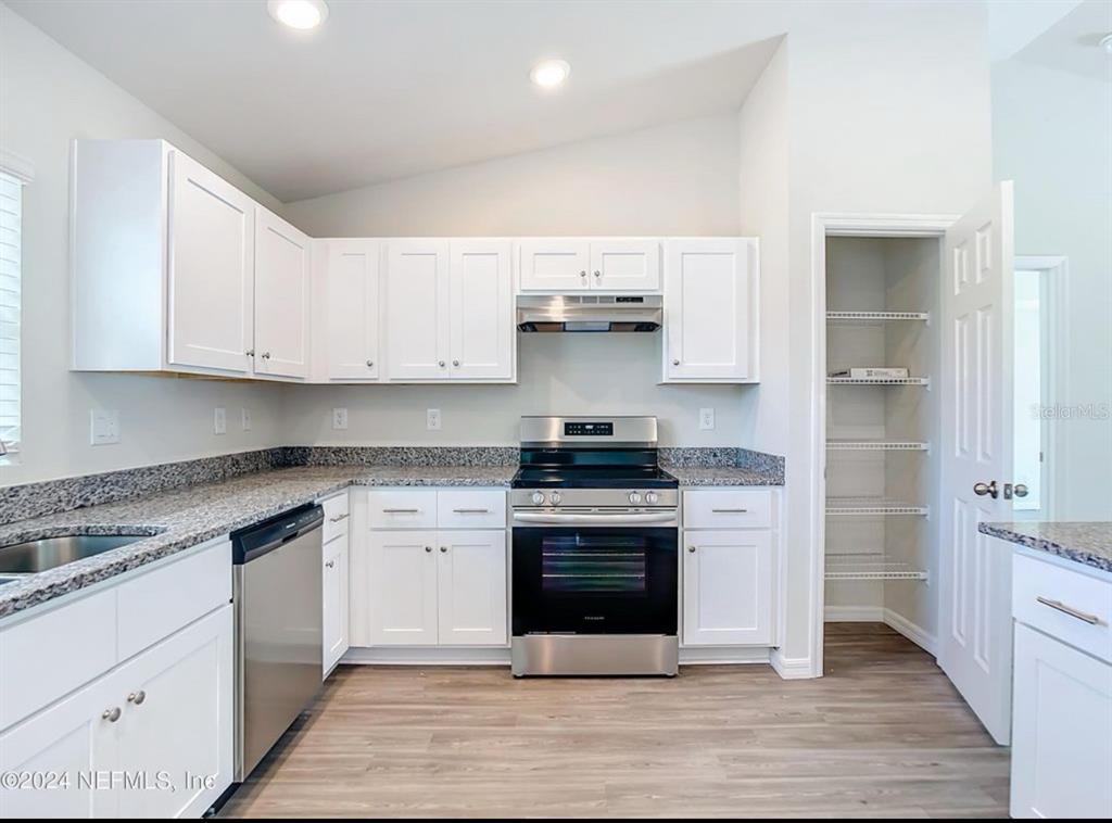 A kitchen features white cabinets, granite countertops, stainless steel appliances, and a walk-in pantry — 315 MARION OAKS CRSE ROAD, OCALA, FL