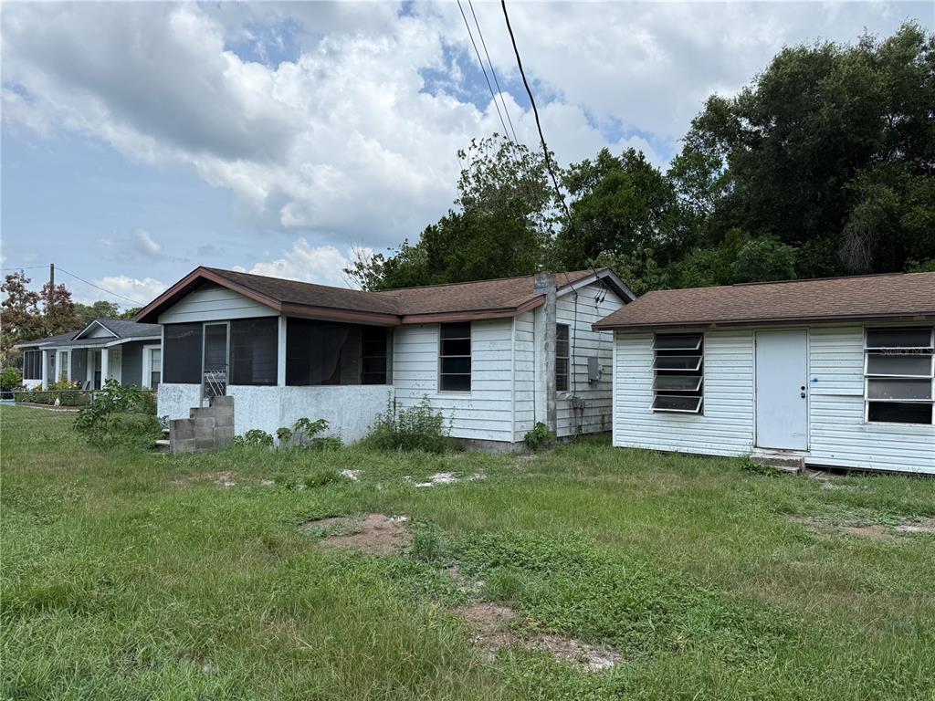 A single-story house with white siding and a screened porch stands next to a shed — 26 ATLANTIC AVENUE, MASCOTTE, FL