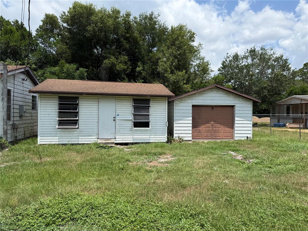 A small white house with a brown roof stands next to a detached garage — 26 ATLANTIC AVENUE, MASCOTTE, FL