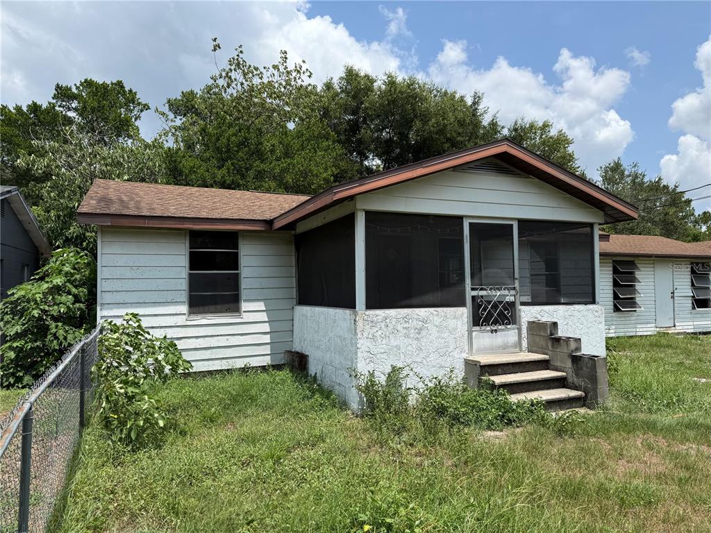 A small, single-story house with white siding, a screened-in front porch, and a brown roof — 26 ATLANTIC AVENUE, MASCOTTE, FL