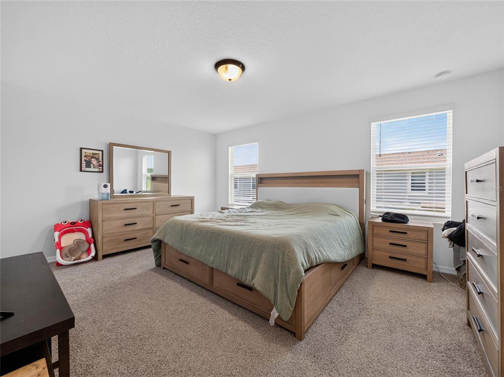 A bedroom features a wooden bed frame, matching dresser, nightstand, and beige wall-to-wall carpeting — 4368 RANCH HOUSE ROAD, ST CLOUD, FL