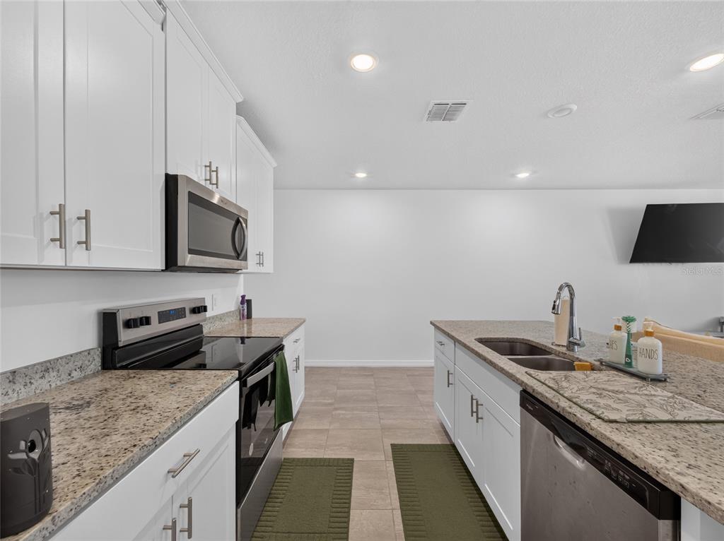 A kitchen features white cabinets, granite countertops, stainless steel appliances, and a central island — 4368 RANCH HOUSE ROAD, ST CLOUD, FL