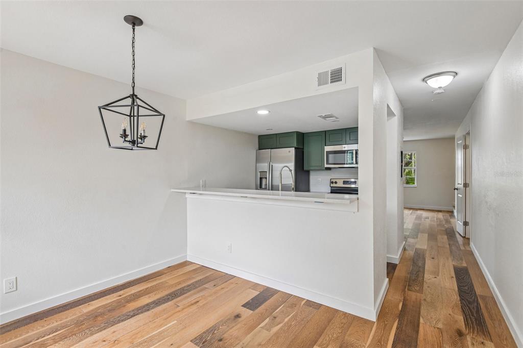 A dining area with a pendant light opens to a kitchen featuring green cabinets — 7192 E BANK DRIVE UNIT 7192, TAMPA, FL