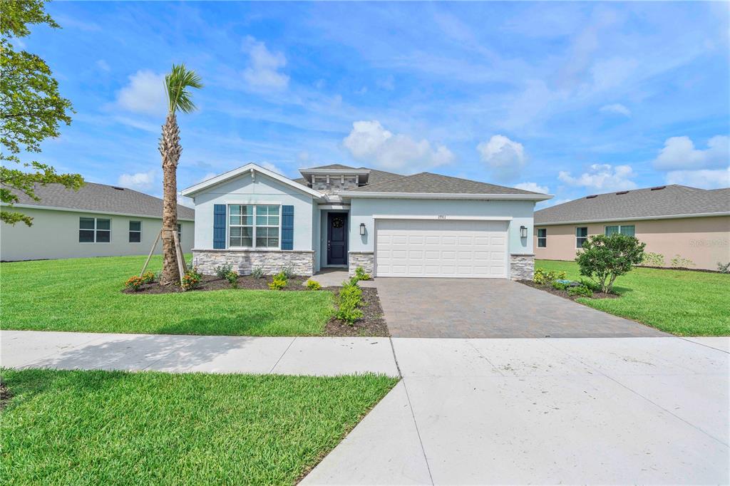 A single-story house with a light blue exterior, stone accents, and a two-car garage — 17911 SHADE TREE LOOP, PUNTA GORDA, FL