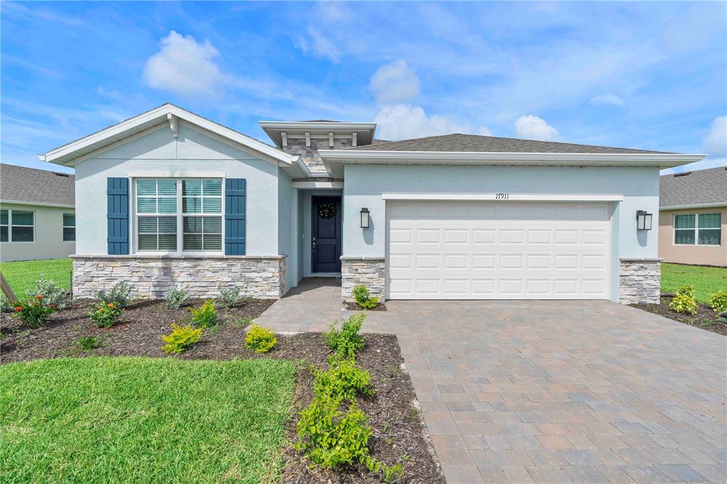 A single-story house with a light blue exterior, stone accents, and a two-car garage — 17911 SHADE TREE LOOP, PUNTA GORDA, FL