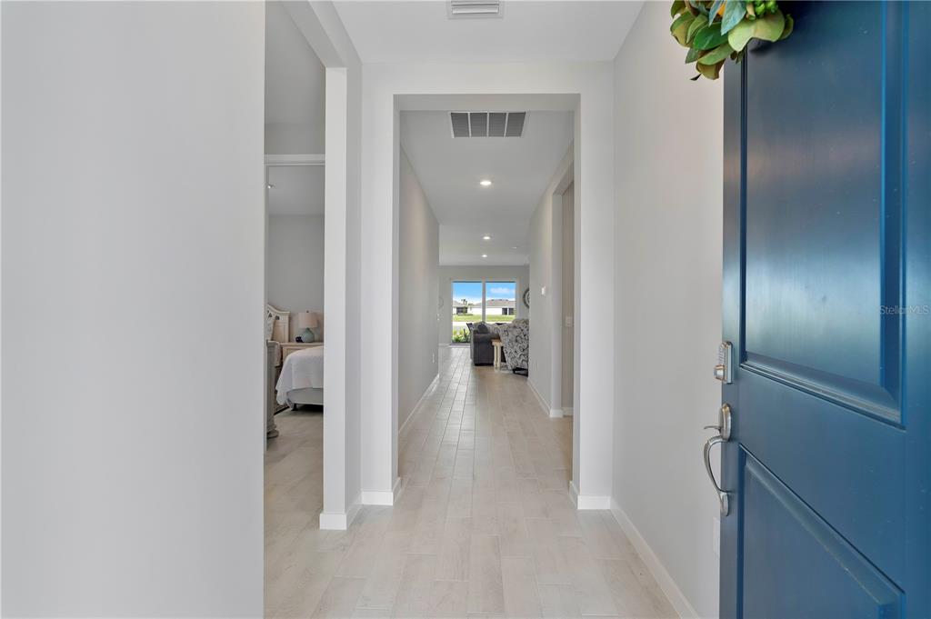 A view from an open blue front door into a hallway with light-colored flooring — 17911 SHADE TREE LOOP, PUNTA GORDA, FL