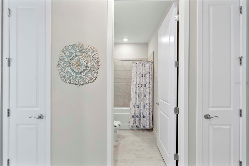 A hallway with two closed doors leads to a bathroom featuring a shower curtain — 17911 SHADE TREE LOOP, PUNTA GORDA, FL